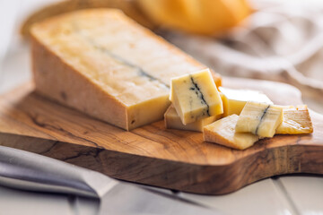 Morbier cheese. Delicious french cheese with mold on cutting board on white table.
