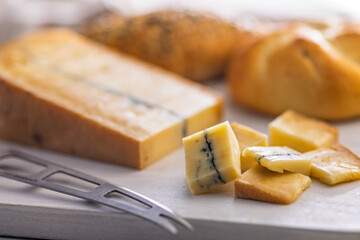 Morbier cheese. Delicious french cheese with mold on cutting board on white table.