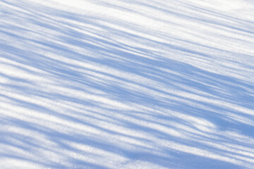A peaceful winter background photo featuring a snow field with blue shadow lines