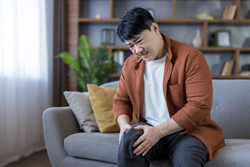 Asian man suffering from sharp knee joint pain