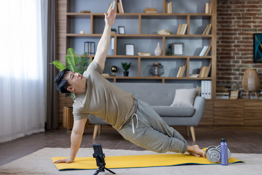 Man doing side plank exercise using smartphone at home