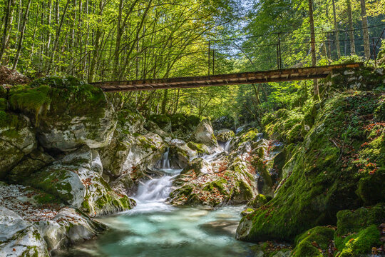 Breathtaking river surrounded by vibrant foliage and a rustic bridge in Sunik, Lepena valley Slovenia, perfect for nature lovers and travelers seeking peace.
