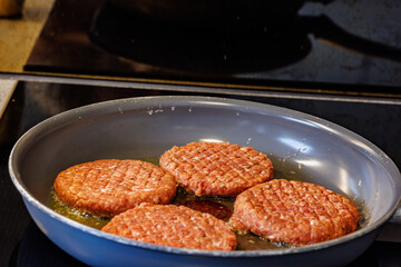 Juicy burger patties sizzling in hot oil, creating delicious homemade meals and culinary delights.