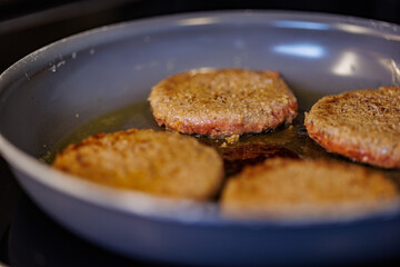 Juicy burger patties sizzling in hot oil on a stovetop pan, ready for delicious meals