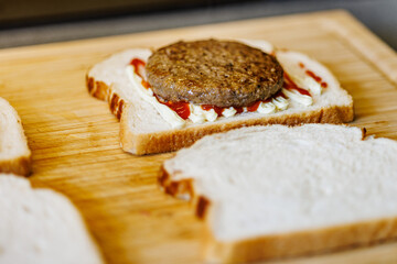 Juicy burger patty on white bread with ketchup and mayo, ready for a delicious meal