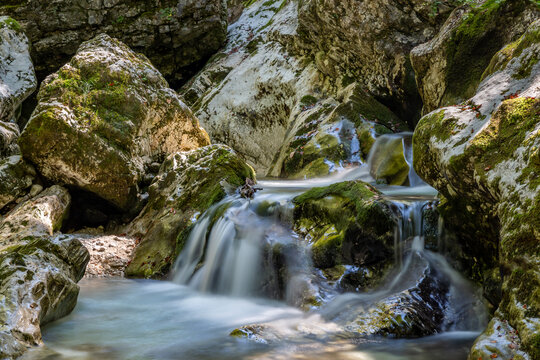 Clear waters flow gently over mossy rocks in Sunik, lepena Valley,, Slovenia, creating a peaceful natural retreat ideal for travelers seeking tranquility.