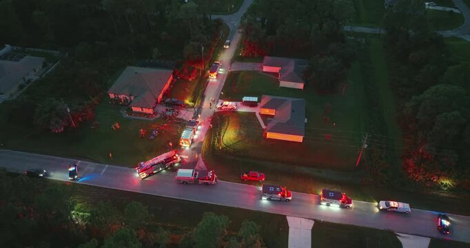 Firefighters investigating fire hazard on residential street in North Port in Florida. Bright flashing lights at night.
