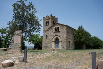 The historic Sant Francesc s'hi Moria Church in Osona (Vic, Catalonia), a beautiful example of ancient Romanesque stone architecture under a bright sky.