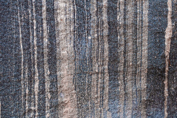 Fototapeta premium Closeup of a natural stone surface featuring vertical striations, rough texture, and earthy tones. Ideal as a background, abstract design element, or geological texture for use in construction design.
