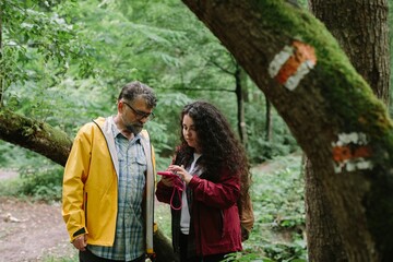 Father daughter hiking in forest navigating with smart device