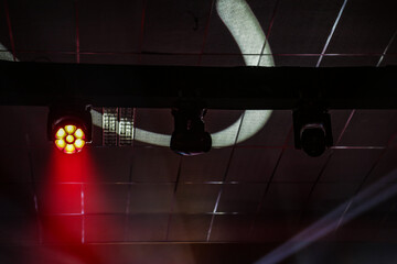 Luzes de palco, com fachos e projeções de luzes no teto escuro de um teatro. © Angela