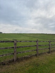 Wooden fence on a green field landscape in the Cotswolds, England