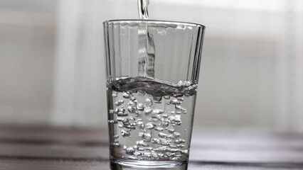Pouring Water into a Glass on a Wooden Table