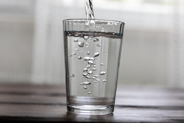 Pouring Water into a Glass on a Wooden Table