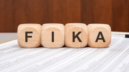 Wooden blocks with FIKA letters on financial document background