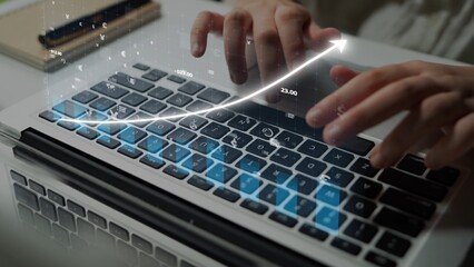 Close-up of hands typing on a laptop keyboard with a digital overlay illustrating growth and analytics, ideal for business or technology themes in contemporary settings. Copula