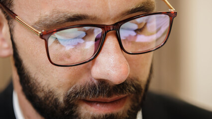 Close-up of a businessman wearing glasses. The reflection in his glasses shows documents and the signing of a contract. Concept of business approach and decision-making.