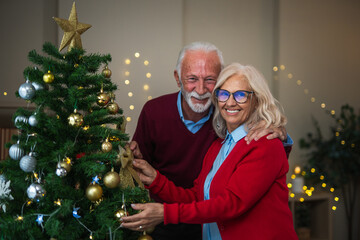 Senior couple decorating christmas tree together during holidays