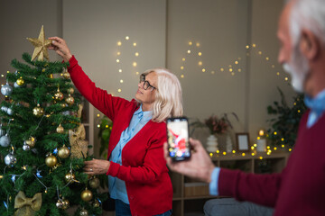 Senior couple sharing holiday cheer decorating christmas tree