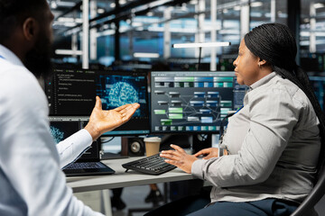 Fototapeta premium Engineering team working together to setup data center equipment needed to run artificial intelligence and machine learning. African american server room coworkers using AI tools