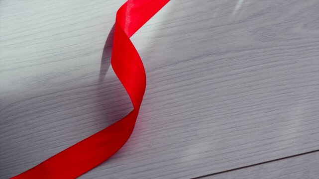 Red satin ribbon on a white wooden floor.
Durable red ribbon for wrapping gifts before the holidays.
Holiday, Christmas, wrapping