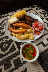 Traditional dish of fritada made with pork and served with corn, beans, cheese, fried banana, fresh salad, and Hot sauce.