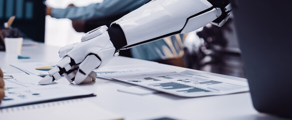 A robotic arm interacts with business analysts in a modern workspace, highlighting collaboration in data analysis and enhancing productivity through technology.Noogenesis