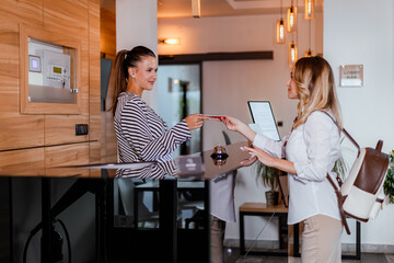 Hotel receptionist helps guest check in and provides room access card in modern lobby setting