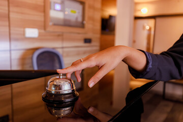Hotel receptionist rings bell to signal guest check-in at modern lobby during daytime