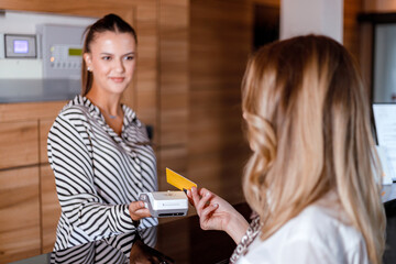 Receptionist assists guest with check-in at hotel front desk during daytime