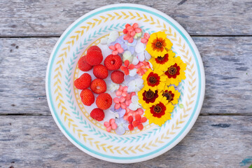 Plate with fruits and flowers on a wooden table