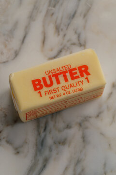 one 4oz stick of Unsalted butter in wrapping on white marble kitchen counter