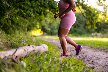 African american plus size young woman exercising in the forest and looking determined