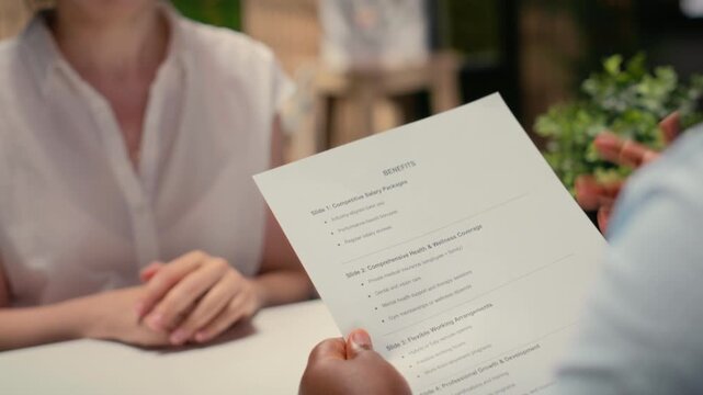 Close up of applicant reviewing monthly perks and medical subscription options, meeting with a recruiter to go over the benefits package for work contract. Reaching an agreement. Camera B.