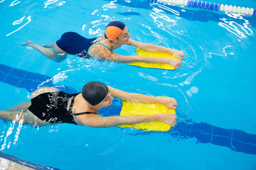 Women training with kickboards in swimming pool