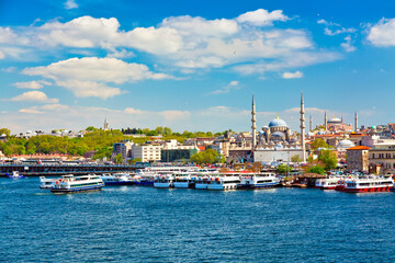 Eminonu district in Istanbul with New Mosque or Valide Sultan Mosque and Hagia Sophia with ferry ships during summer sunny day. Istanbul, Turkiye