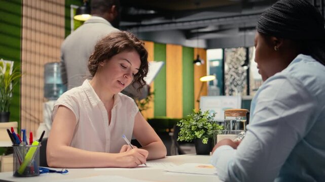 Confident woman signing a contract with human resources assistant, joining organization after legal paperwork review and agreement. Successful recruitment process for business growth. Camera A.