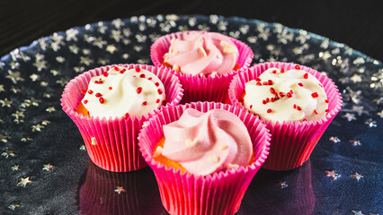 Beautiful pink frosted cupcakes with delicate sprinkles, arranged on an elegant white plate....