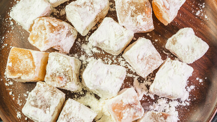 A plate of Turkish delight sweets ready to be served. The soft, square candies are dusted with powdered sugar, arranged neatly on a simple plate for an elegant presentation.
