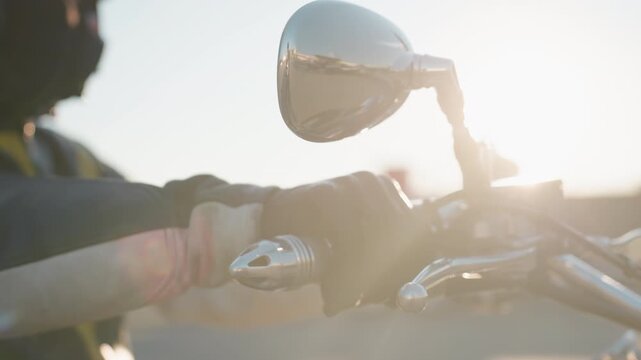 Close up of biker hand gripping throttle on motorcycle handle, wearing leather glove, mirror reflecting city scene in soft daylight, emphasizing control, strength, speed, and freedom of urban riding