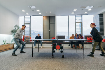 Obraz premium Business colleagues take a break from work to enjoy a game of table tennis, fostering teamwork and camaraderie in the workplace