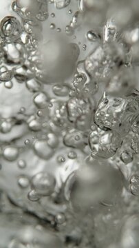 Macro close-up view of bubbles floating in a pot of boiling water, creating a mesmerizing texture. Concept of beverage