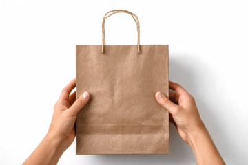 Hands holding a brown paper shopping bag on white.