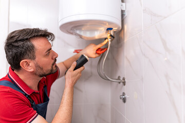 Skilled technician repairing water heater in modern bathroom setting during daylight hours