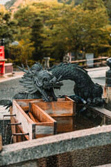 Kyoto, Japan: Dragon statue spouting water at a Temizuya/Chōzuya purification fountain. Temple or shrine grounds detail, religious ritual washing.