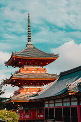 Obraz premium Kyoto, Japan: Kiyomizu-dera Temple red pagoda (Sanjū-no-tō) next to the tiled roof of a temple hall. Vermillion Buddhist architecture, close-up.