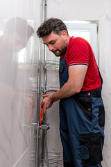 Man working on plumbing repairs in a modern bathroom during daylight hours