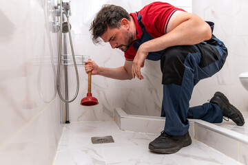 Plumber unclogs shower drain with plunger in residential bathroom