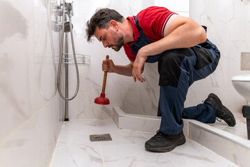 Plumber unclogs shower drain with a plunger during midday home repair session