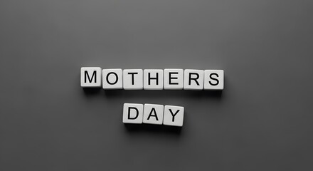 Fototapeta premium White letter tiles spelling 'MOTHERS DAY' arranged on a dark grey background, celebrating the special occasion.